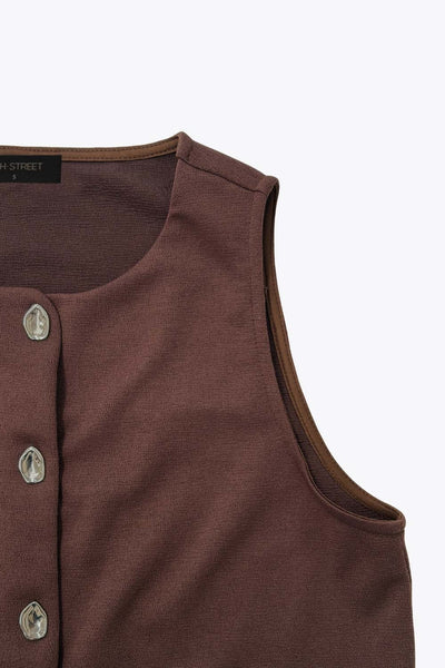 Chaleco corto de fit recto, cuello redondo y cierre frontal con hilera de botones en contraste. Detalle abertura v en bajo.