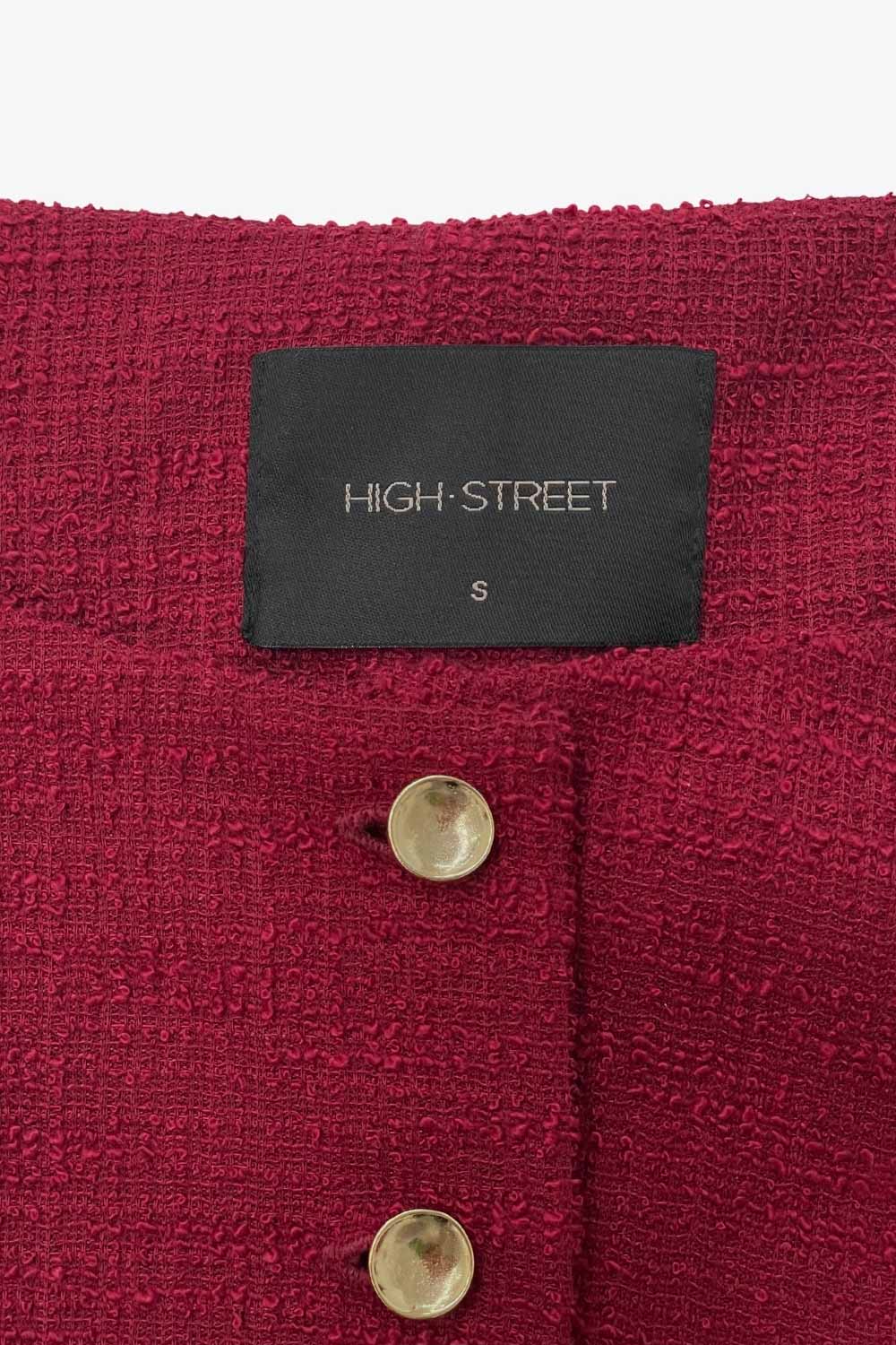 Chaleco corto de bouclé, fit recto, cuello barco y cierre frontal con hilera de botones en contraste. Detalle abertura v en bajo y vivos decorativos frontales.