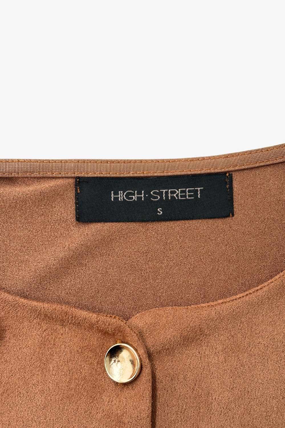 Chaleco corto de gamuza, fit recto, cuello redondo y cierre frontal con hilera de botones en contraste. Detalle de abertura frontal en bajo.