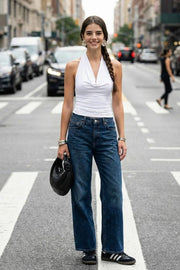 Top corto ajustado de cuello halter con escote fluido, sin mangas, escote en espalda, cierre posterior con botón y ojal.