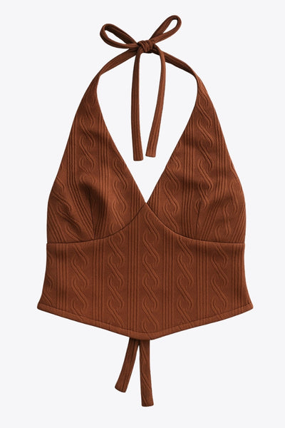 Top corto de cuello halter, lazo amarrable posterior, escote v con cortes frontales, bajo v frontal, escote en espalda y lazo amarrable posterior. Detalle de textura en tejido.