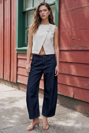 Top corto de fit recto, cuello redondo, sin mangas, cruce frontal en diagonal con botones decorativos en contraste, cierre posterior con botón y ojal.