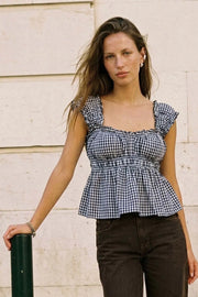 Top corto de estampado cuadros, escote v redondeado y manga corta con rib elástico y olanes en borde, elástico en cintura y peplum con olanes en bajo.