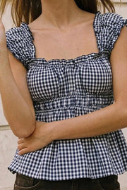 Top corto de estampado cuadros, escote v redondeado y manga corta con rib elástico y olanes en borde, elástico en cintura y peplum con olanes en bajo.