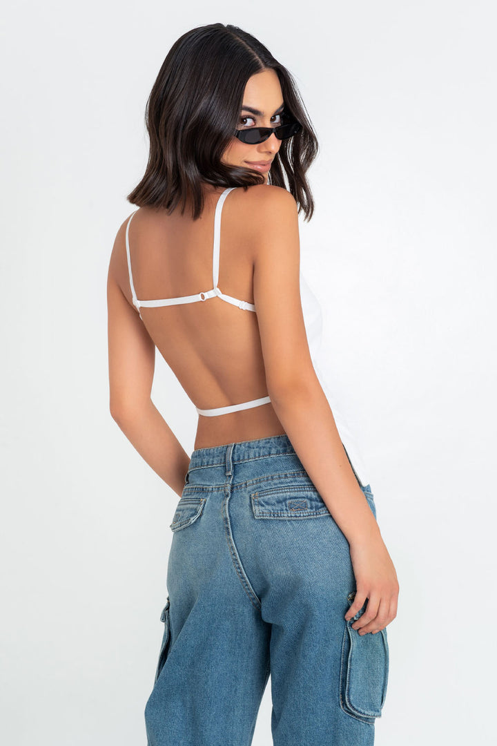 Woman in white top and blue jeans looking over shoulder.