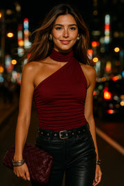 Top satinado asimétrico, de fit ajustado, detalles plisados laterales y en hombro, sin mangas, un hombro, escote diagonal y choker con plisados. Cierre posterior con botón y ojal.