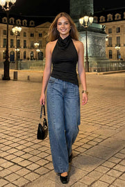 Top halter corto de fit ajustado, sin mangas, cuello halter fluido con plisados y escote en espalda. Detalle de bajo diagonal asimétrico.