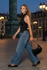 Top halter corto de fit ajustado, sin mangas, cuello halter fluido con plisados y escote en espalda. Detalle de bajo diagonal asimétrico.