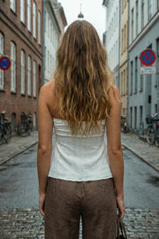 Top corto halter con lazo amarrable posterior, escote corazón con jareta ajustable y plisados frontales. Detalle de olanes y bajo asimétrico frontal con abertura.