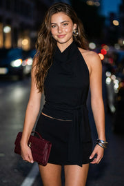 Top halter de cuello alto fluido, sin mangas, escote en espalda, fit ajustado, cierre posterior con lazo amarrable, botón y ojal.