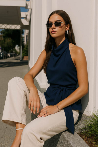 Top halter de cuello alto fluido, sin mangas, escote en espalda, fit ajustado, cierre posterior con lazo amarrable, botón y ojal.