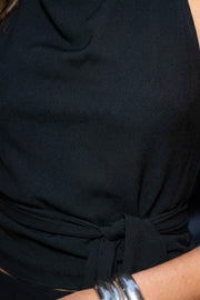 Top halter de cuello alto fluido, sin mangas, escote en espalda, fit ajustado, cierre posterior con lazo amarrable, botón y ojal.