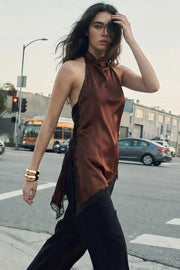 Blusa halter satinada de fit fluido, cuello halter fluido, sin mangas, bajo asimétrico con abertura lateral y encaje decorativo en contraste. Detalle de escote fluido en espalda, cierre posterior con botón y ojal.