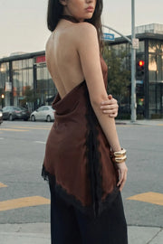 Blusa halter satinada de fit fluido, cuello halter fluido, sin mangas, bajo asimétrico con abertura lateral y encaje decorativo en contraste. Detalle de escote fluido en espalda, cierre posterior con botón y ojal.