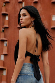 Top corto halter con lazo posterior, sin mangas, cut out frontal con cruce y fit fluido. Escote en espalda y cierre posterior con nudo amarrable.