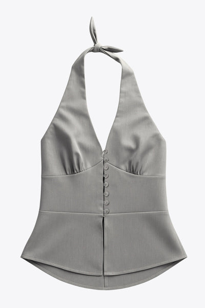 Top corto de cuello halter con nudo amarrable posterior, escote v con cortes y plisados decorativos frontales, fit ajustado, escote en espalda con fruncido posterior, cierre frontal con hilera de botones y bajo curveado con abertura.