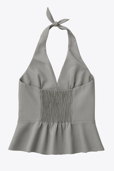 Top corto de cuello halter con nudo amarrable posterior, escote v con cortes y plisados decorativos frontales, fit ajustado, escote en espalda con fruncido posterior, cierre frontal con hilera de botones y bajo curveado con abertura.