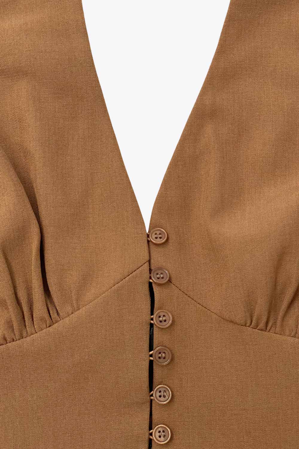 Top corto de cuello halter con nudo amarrable posterior, escote v con cortes y plisados decorativos frontales, fit ajustado, escote en espalda con fruncido posterior, cierre frontal con hilera de botones y bajo curveado con abertura.