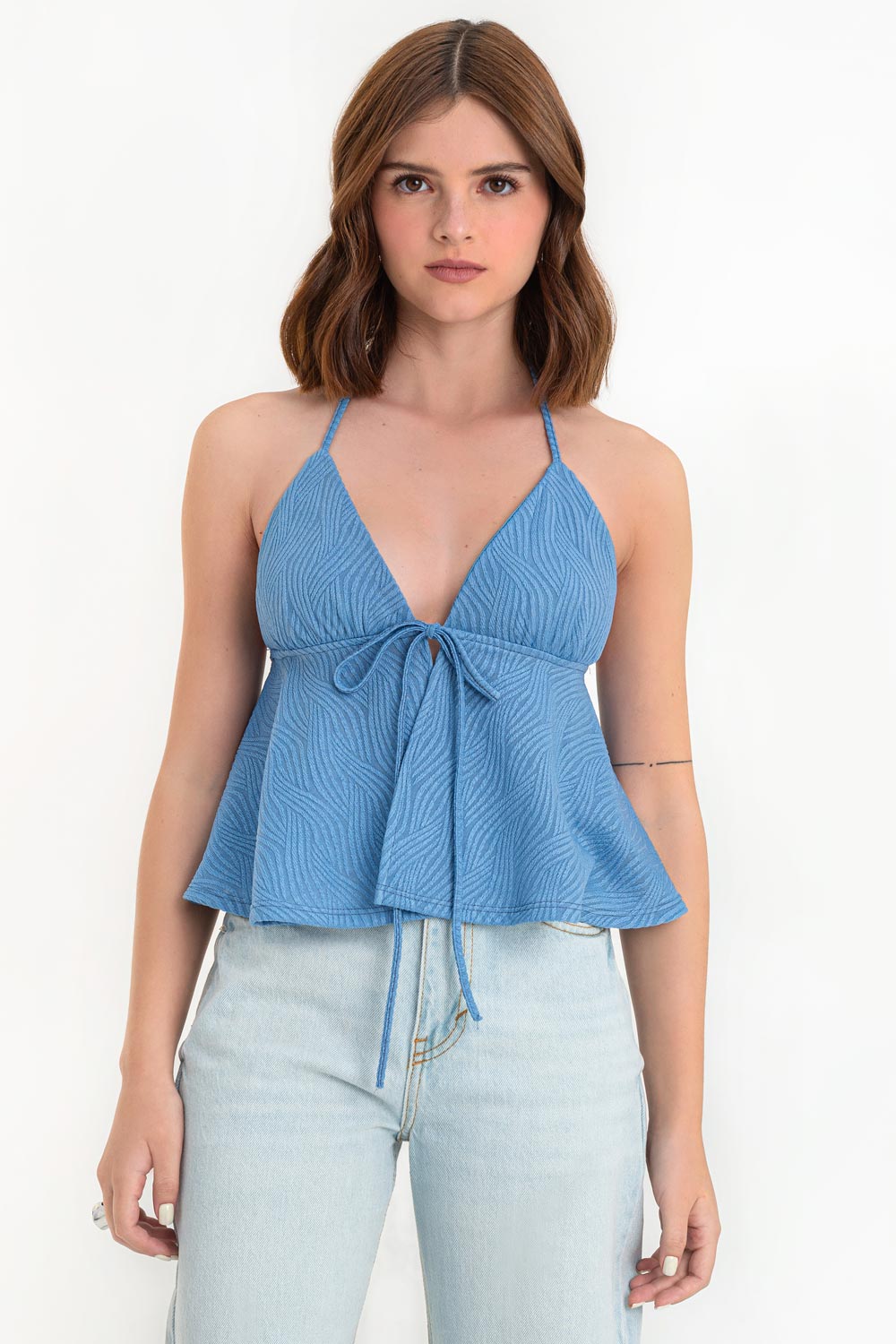 Top corto halter de escote v con lazo amarrable frontal, rib elástico en espalda, tirantes halter con lazo amarrable posterior y abertura frontal en bajo. Detalle de peplum olanes y textura en tejido.