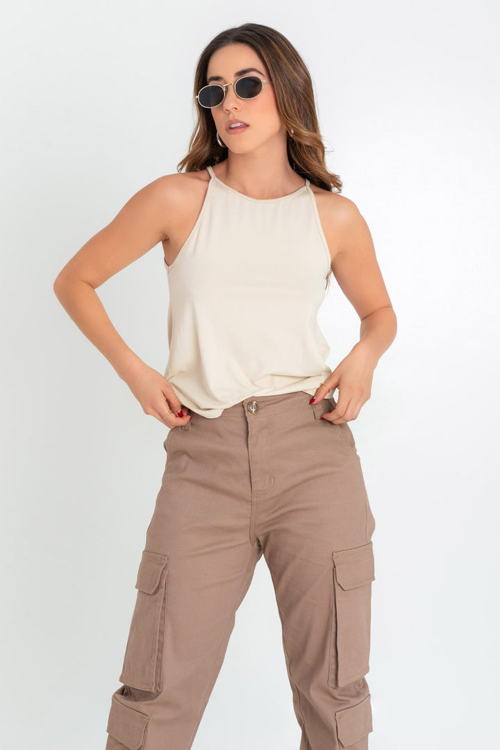Fashionable woman posing in beige tank top, brown cargo pants, and sunglasses.