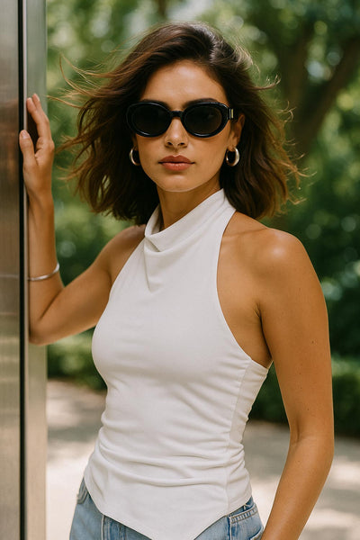 Top halter corto de fit ajustado, sin mangas, cuello halter fluido con plisados y escote en espalda. Detalle de bajo diagonal asimétrico.