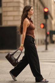 Top halter corto de fit ajustado, sin mangas, cuello halter fluido con plisados y escote en espalda. Detalle de bajo diagonal asimétrico.