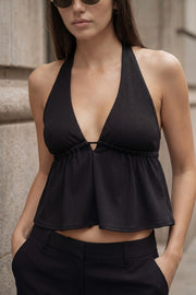 Top canalé de cuello halter con nudo amarrable posterior, escote v con plisados frontales, rib elástico en cintura y peplum olanes. Detalle de escote en espalda con lazo amarrable posterior.