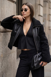 Top canalé de cuello halter con nudo amarrable posterior, escote v con plisados frontales, rib elástico en cintura y peplum olanes. Detalle de escote en espalda con lazo amarrable posterior.