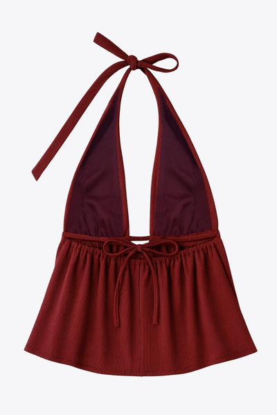 Top canalé de cuello halter con nudo amarrable posterior, escote v con plisados frontales, rib elástico en cintura y peplum olanes. Detalle de escote en espalda con lazo amarrable posterior.