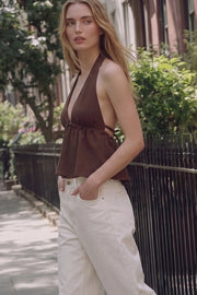 Top corto de cuello halter con lazo amarrable posterior, escote v con plisados, rib elástico en espalda y lazo amarrable en espalda. Detalle de peplum olanes en bajo y textura en tejido.