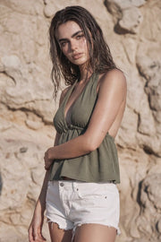 Top corto de cuello halter con lazo amarrable posterior, escote v con plisados, rib elástico en espalda y lazo amarrable en espalda. Detalle de peplum olanes en bajo y textura en tejido.