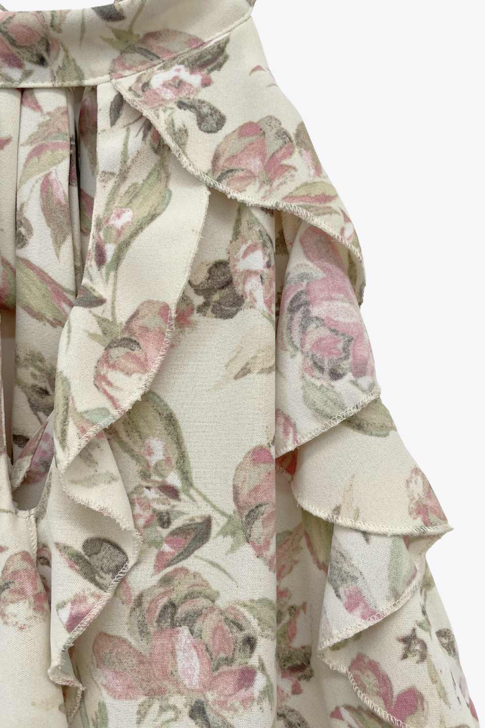 Blusa de fit fluido, estampado floral, sin mangas, cuello halter, capas de olanes frontales y en bajo asimétrico. Cierre posterior con lazo amarrable.