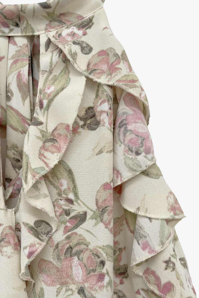 Blusa de fit fluido, estampado floral, sin mangas, cuello halter, capas de olanes frontales y en bajo asimétrico. Cierre posterior con lazo amarrable.