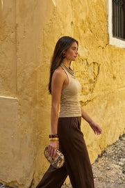 Top halter de fit ajustado, cuello alto fluido, sin mangas, plisados en costados y cierre posterior con botón y ojal.