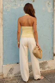 Top halter de fit ajustado, cuello alto fluido, sin mangas, plisados en costados y cierre posterior con botón y ojal.