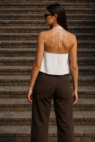 Top corto halter de escote v con lazo amarrable frontal, rib elástico en espalda, tirantes halter con lazo amarrable posterior y abertura frontal en bajo. Detalle de peplum olanes y textura en tejido.