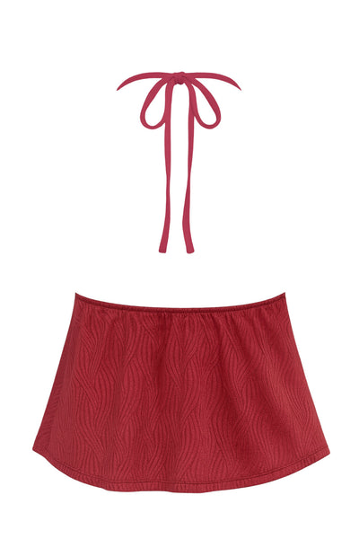 Top corto halter de escote v con lazo amarrable frontal, rib elástico en espalda, tirantes halter con lazo amarrable posterior y abertura frontal en bajo. Detalle de peplum olanes y textura en tejido.