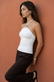 Top de fit ajustado, cuello halter con hebilla frontal en contraste, plisados y lazo amarrable posterior.