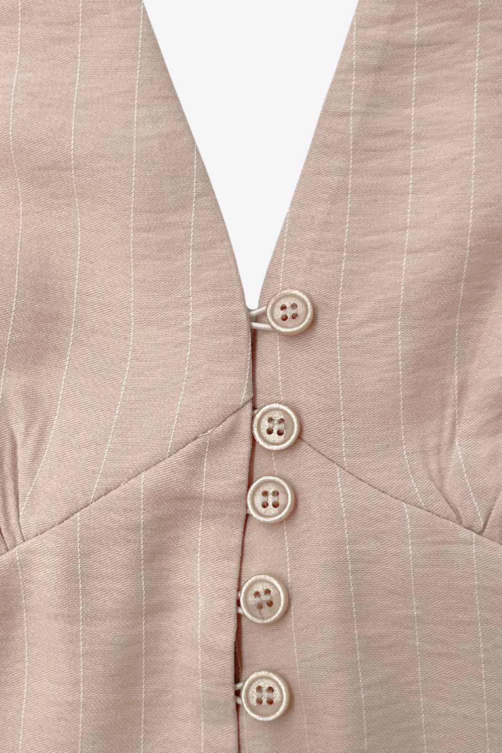 Top corto de estampado rayas, cuello halter con nudo amarrable posterior, escote v con cortes y plisados decorativos frontales, fit ajustado, escote en espalda con fruncido posterior, cierre frontal con hilera de botones y abertura en bajo.