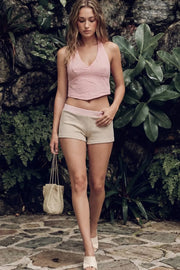 Top corto halter con lazo amarrable posterior, fit ajustado, escote v con cortes frontales, bajo v frontal, escote en espalda y cierre posterior con nudo amarrable. Detalle de textura en tejido.