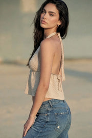 Top corto de cuello halter con lazo amarrable posterior, escote v con plisados, rib elástico en espalda y lazo amarrable en espalda. Detalle de peplum olanes en bajo y textura en tejido.