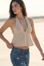 Top corto de cuello halter con lazo amarrable posterior, escote v con plisados, rib elástico en espalda y lazo amarrable en espalda. Detalle de peplum olanes en bajo y textura en tejido.