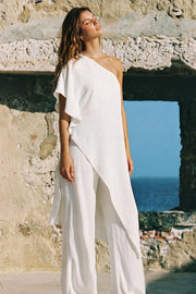 Blusa tipo túnica asimétrica, escote diagonal, una manga corta seguida con olanes, fit fluido y bajo asimétrico.