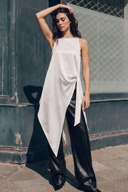 Blusa larga satinada de fit fluido, cuello halter, sin mangas, bajo asimétrico, plisados en costado con abertura y nudo decorativo , cierre posterior con botón y ojal.