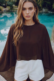 Blusa tipo capa de fit fluido, manga larga amplia seguida, cuello redondo, cierre posterior con botón y ojal.