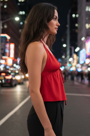 Top corto satinado de escote v con lazo amarrable frontal, rib elástico en espalda, tirantes halter con lazo amarrable posterior y abertura frontal en bajo. Detalle de peplum olanes en bajo.