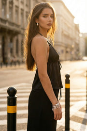 Top corto satinado de escote v con lazo amarrable frontal, rib elástico en espalda, tirantes halter con lazo amarrable posterior y abertura frontal en bajo. Detalle de peplum olanes en bajo.