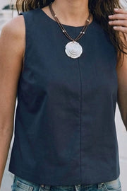 Blusa básica de cuello redondo, sin mangas, fit recto, costura frontal, cierre posterior con botón y ojal.