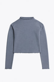 Top de manga larga con hombro caído, cuello mock seguido, fit recto, textura en tejido, detalle de rib en borde de bajo y puños.