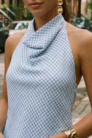 Blusa de estampado cuadros, cuello halter fluido, escote en espalda con lazo amarrable posterior, cierre con botón y ojal.